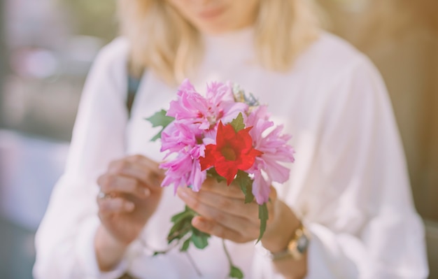 Primo piano della giovane donna che tiene il fiore viola e rosso in mani