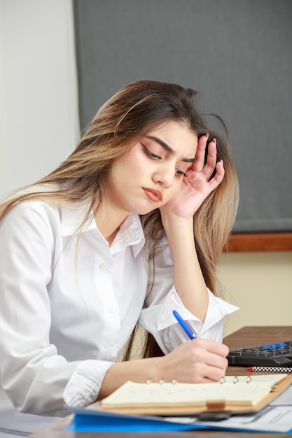 Primo piano della giovane donna seduta alla scrivania e al lavoro