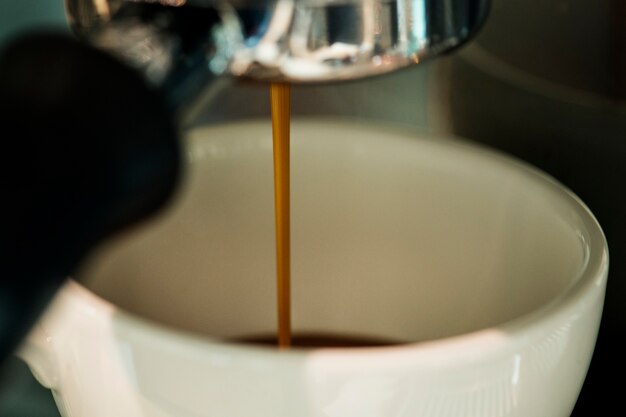Primo piano della macchina del caffè che produce bevanda del caffè espresso