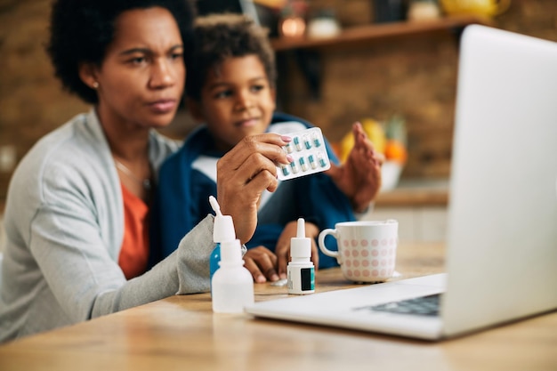 Primo piano della madre nera che si consulta con un medico online sulla medicina per suo figlio