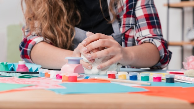 Primo piano della mano che impastano argilla bianca per il mestiere creativo