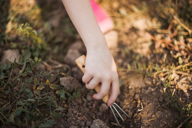 Primo piano della mano che scava il terreno con la forcella di giardinaggio