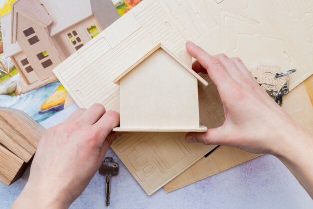 Primo piano della mano che tiene il modello di casa in legno in miniatura