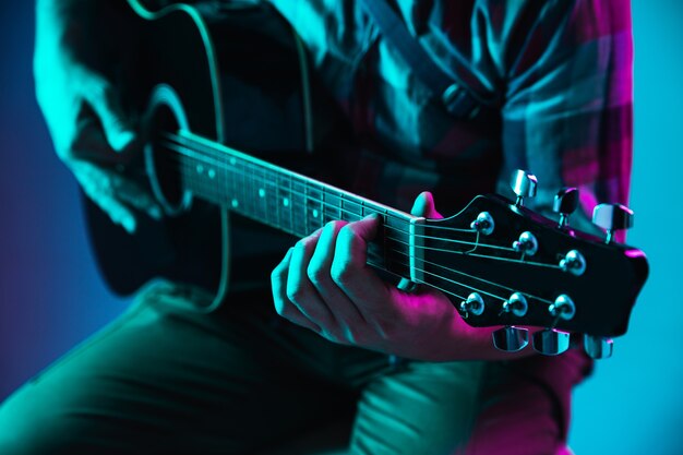 Primo piano della mano del chitarrista che suona la chitarra, macro. Concetto di pubblicità, hobby, musica, festival, intrattenimento. Persona che improvvisa ispirata. Copyspace per inserire immagine o testo. Illuminato al neon colorato.