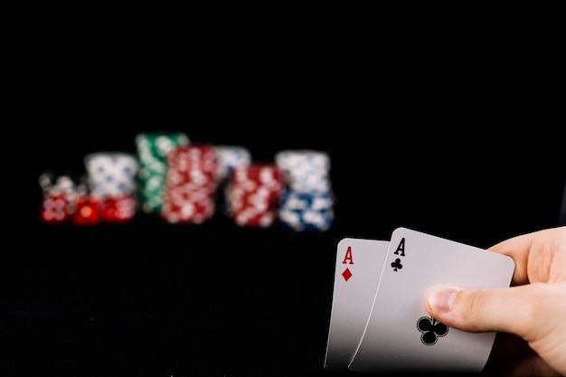 Primo piano della mano del giocatore che tiene due carte da gioco di assi