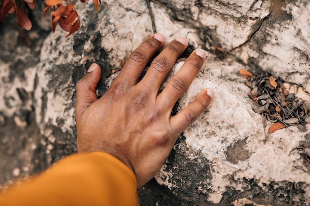 Primo piano della mano dell'escursionista maschio che tocca la roccia