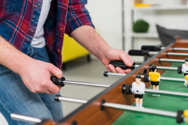 Primo piano della mano dell&#39;uomo che gioca il gioco di calcio del biliardino