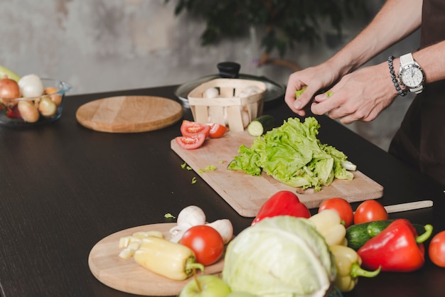 Primo piano della mano dell&#39;uomo che pulisce lattuga sul bancone della cucina