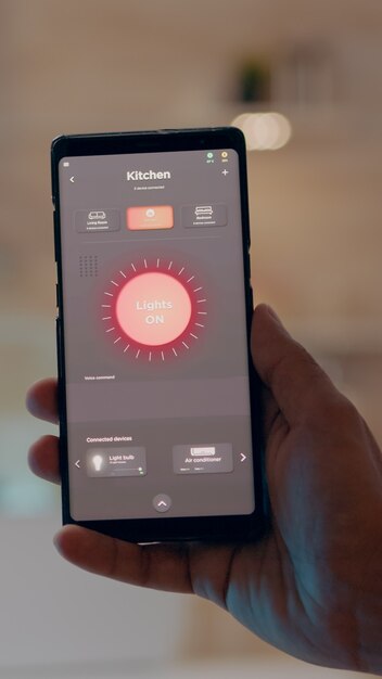Primo piano della mano dell'uomo che tiene il telefono con un software moderno che controlla le luci