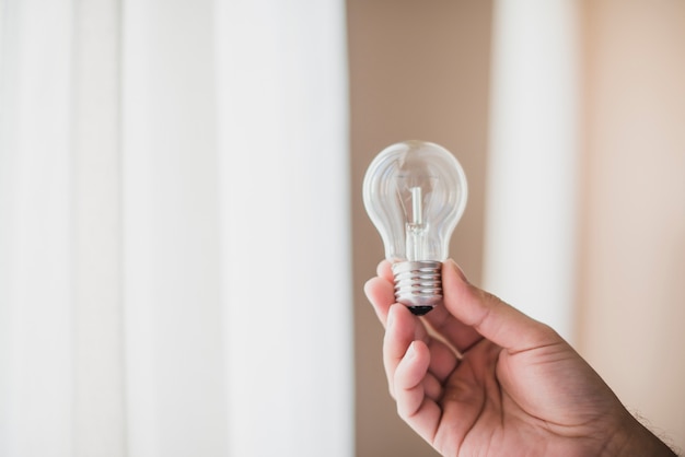 Primo piano della mano dell&#39;uomo che tiene lampadina trasparente