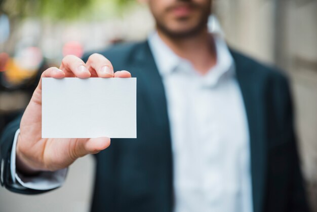 Primo piano della mano dell&#39;uomo d&#39;affari che mostra il biglietto da visita bianco