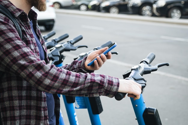 Primo piano della mano dell'uomo utilizzando l'app mobile per il noleggio di scooter elettrici