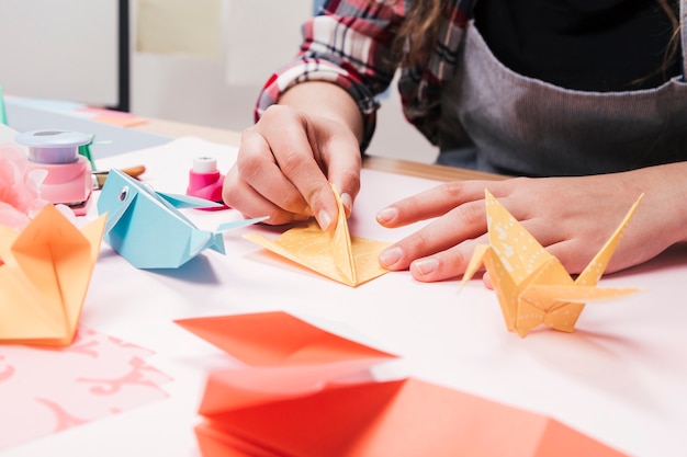 Primo piano della mano della donna che fa il mestiere di arte creativa usando la carta di origami