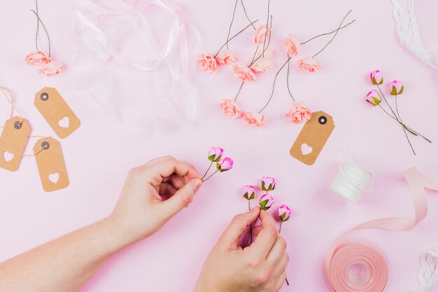 Primo piano della mano della donna che organizza il fiore su sfondo rosa