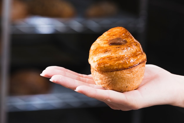 Primo piano della mano della donna che tiene pasta sfoglia dolce appena sfornata