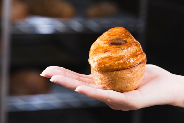 Primo piano della mano della donna che tiene pasta sfoglia dolce appena sfornata