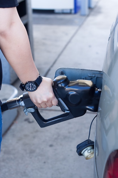 Primo piano della mano della donna mettere gas in auto alla stazione di benzina