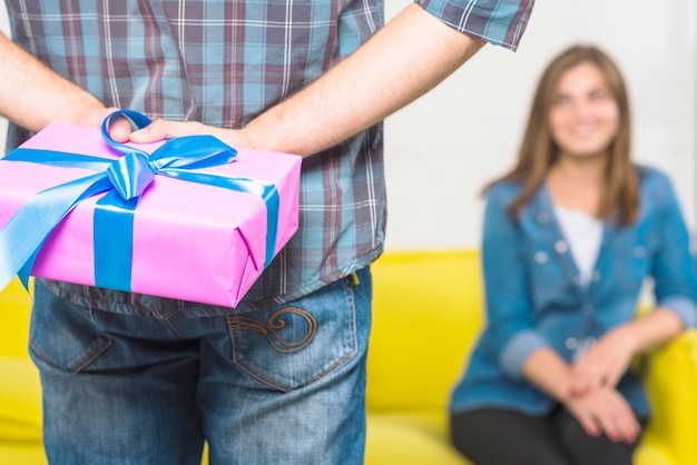 Primo piano della mano di un uomo che nasconde il contenitore di regalo dietro la schiena