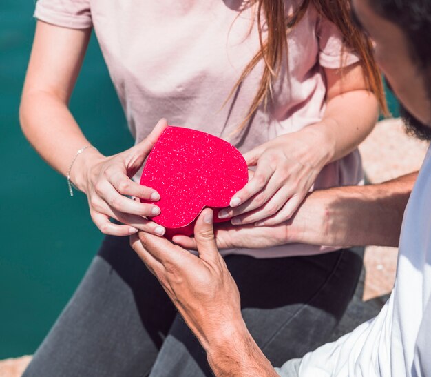 Primo piano della mano di una coppia che tiene a forma di cuore rosso