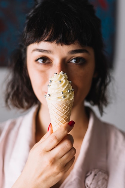 Primo piano della mano di una donna che tiene cono gelato davanti alla sua bocca