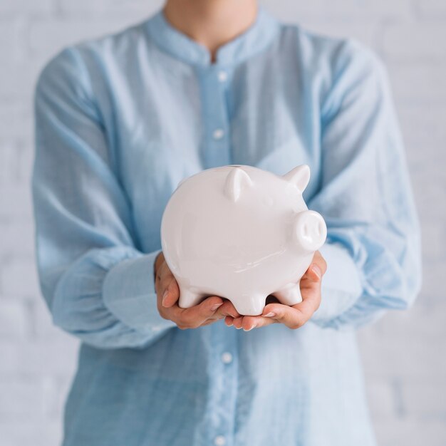 Primo piano della mano di una donna che tiene piggybank