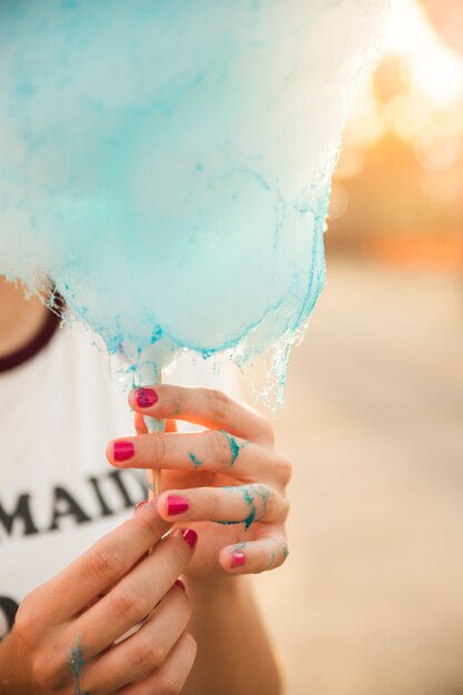 Primo piano della mano di una donna con zucchero filato blu