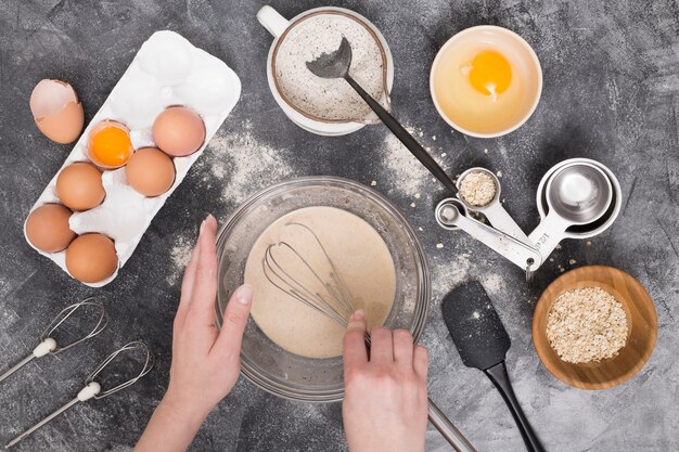 Primo piano della mano di una femmina che prepara gli ingredienti del pane sul contesto concreto