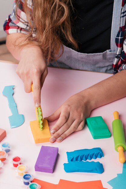 Primo piano della mano donna taglio di argilla colorata sul tavolo