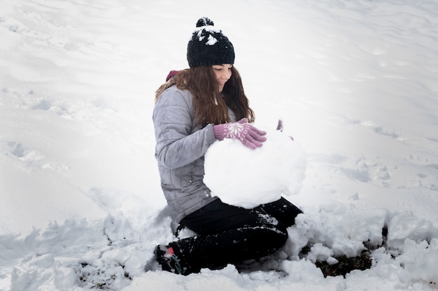 Primo piano della ragazza allegra che fa palla di neve nel paesaggio di inverno