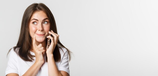 Primo piano della ragazza carina incuriosita che parla al telefono che sembra interessata