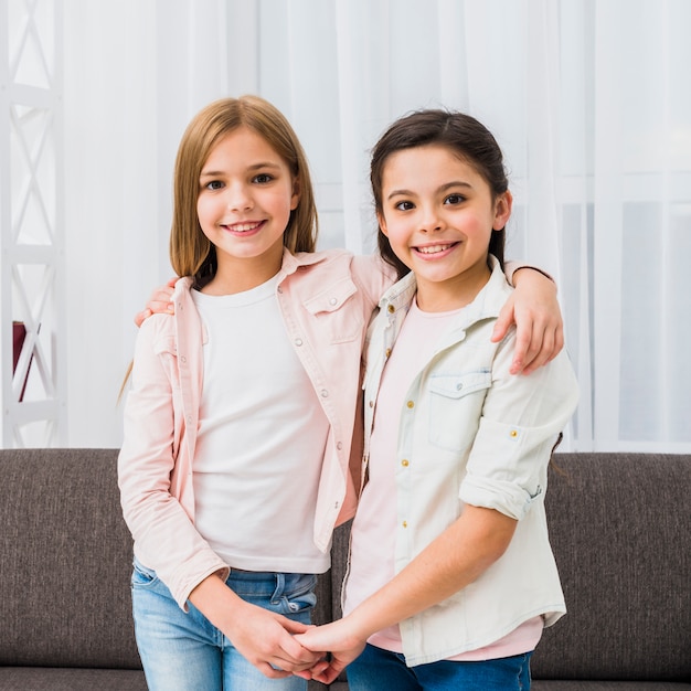 Primo piano della ragazza graziosa che tiene la mano di ciascuno che guarda alla macchina fotografica a casa