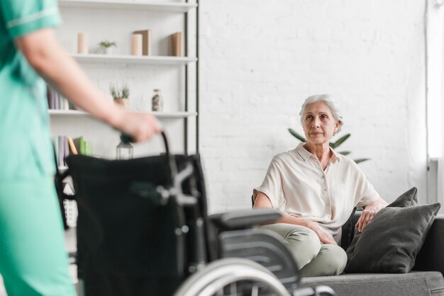 Primo piano della sedia a rotelle della tenuta dell&#39;infermiere davanti al paziente femminile senior