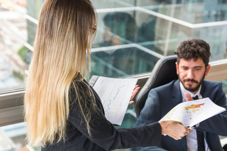 Foto gratuito primo piano della segretaria femminile che dà mappa al responsabile maschio sul posto di lavoro