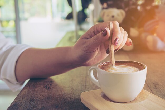 Primo piano della signora che prepara e che mangia la tazza di caffè calda