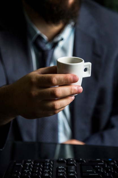 Primo piano della tazza della holding della mano dell&#39;uomo d&#39;affari