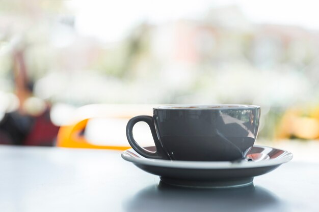 Primo piano della tazza di caffè grigio sul ripiano del tavolo