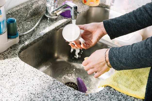 Primo piano della tazza di lavaggio della mano di una donna nel lavandino di cucina