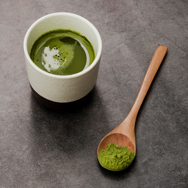 Primo piano della tazza di tè di matcha con il cucchiaio di legno