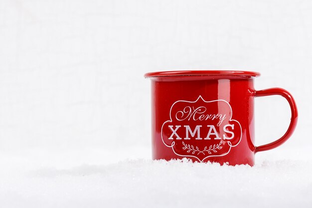 Primo piano della tazza rossa con parole Merry Xmas sulla neve