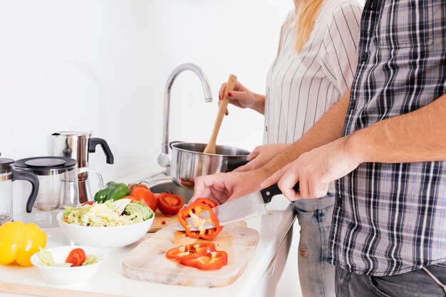 Primo piano delle coppie che preparano alimento nella cucina