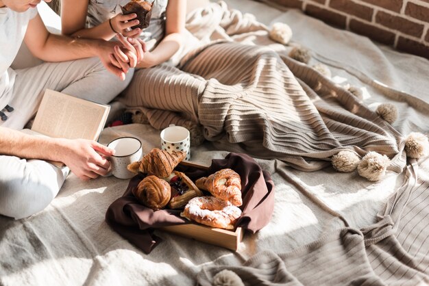 Primo piano delle coppie che tengono la mano di ciascuno che mangia prima colazione