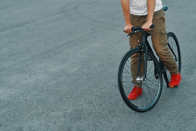 Primo piano delle gambe casuali dell'uomo che guidano bici classica sulla strada di città