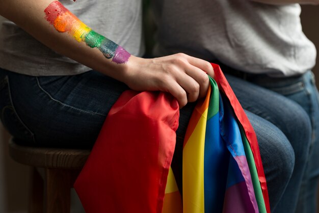 Primo piano delle giovani coppie lesbiche che tengono la bandiera di lbgt a disposizione