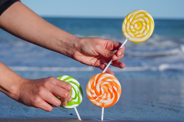 Primo piano delle lecca-lecca dolci variopinte sulla spiaggia sabbiosa