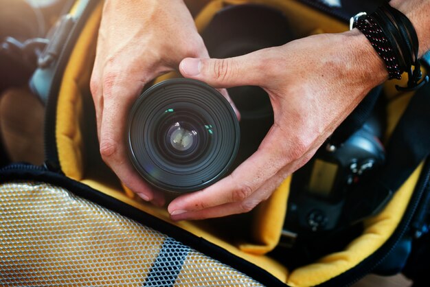 Primo piano delle mani che ottengono l&#39;obiettivo della fotocamera dalla borsa