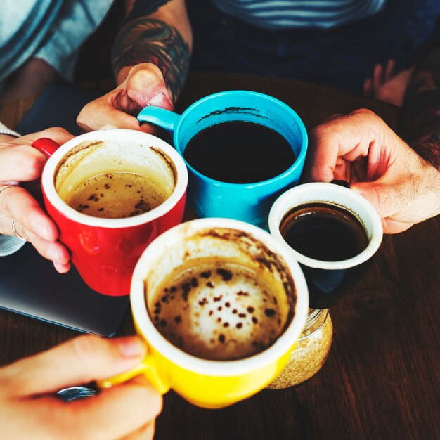 Primo piano delle mani che tengono insieme le tazze di caffè