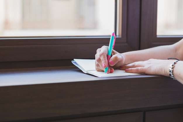 Primo piano delle mani con scrittura della penna in un notebook