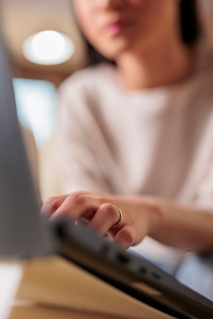 Primo piano delle mani della donna che digitano sul laptop, donna asiatica in background freelance su computer che lavora da casa, progresso tecnologico del lavoro a distanza e web 3.0