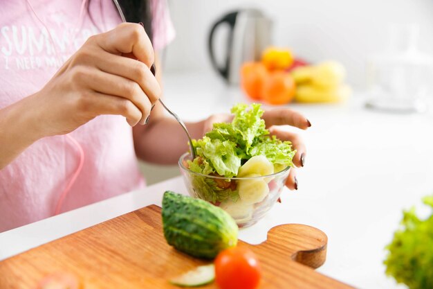 Primo piano delle mani della donna che mescolano insalata nella cucina