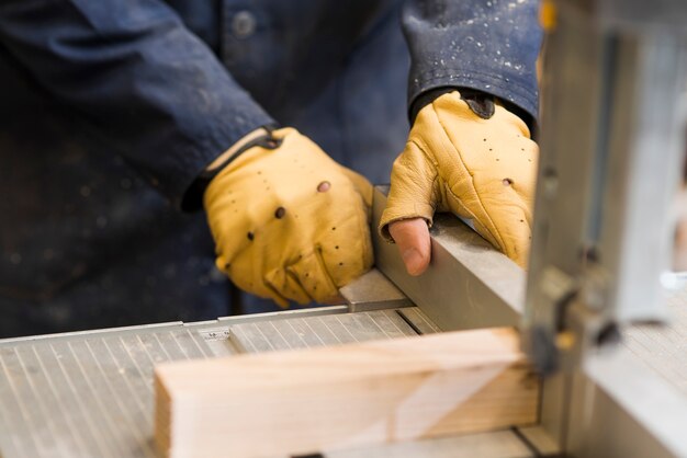 Primo piano delle mani di un carpentiere che lavorano con il blocco di legno sul banco da lavoro